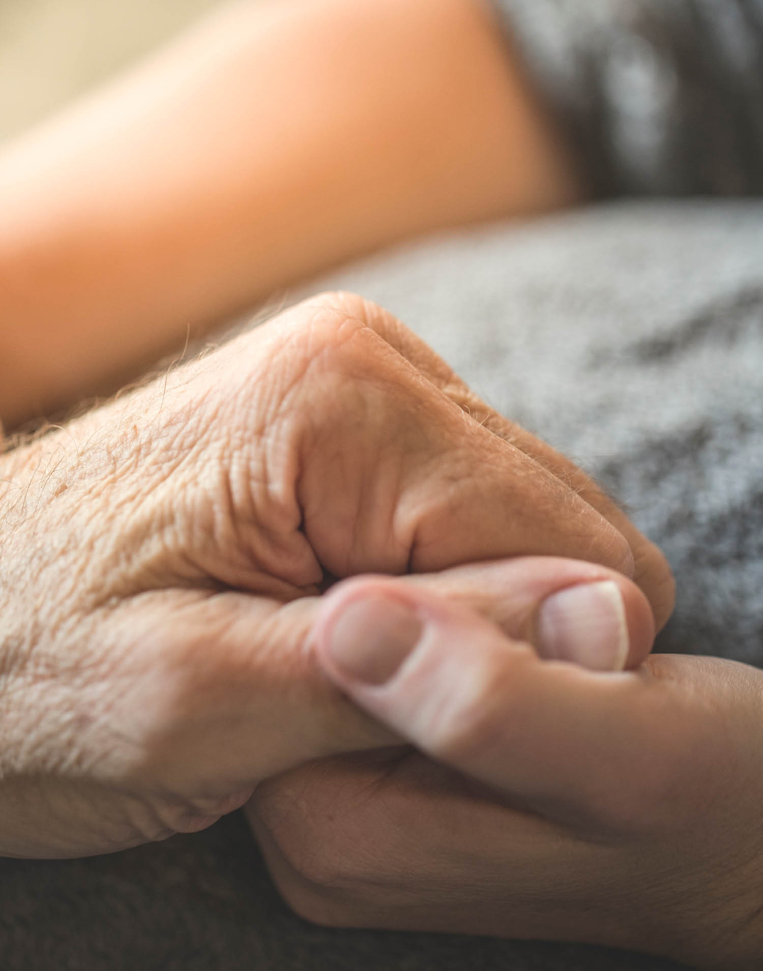 A stock photo of a young woman holding her Elderly fathers hands who is currently being cared for on a home hospice program  Photographed using the Canon EOS 1DX Mark II  Perfect for designs or articles about caring for the elderly or home hospice care and nursing