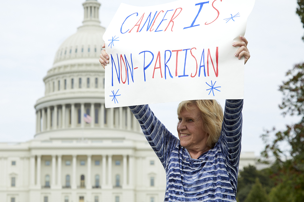 Volunteer holding a sign that reads "Cancer is non partisan"