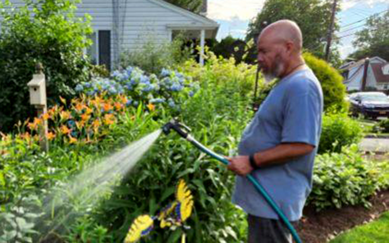 Miguel Melendez using a water hose in the garden.