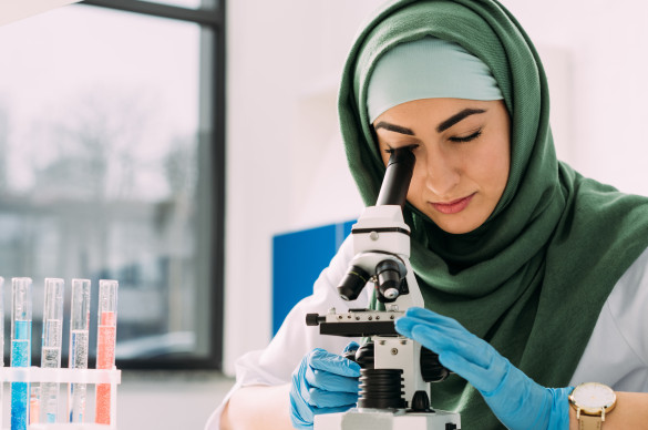 woman looking through a microscope
