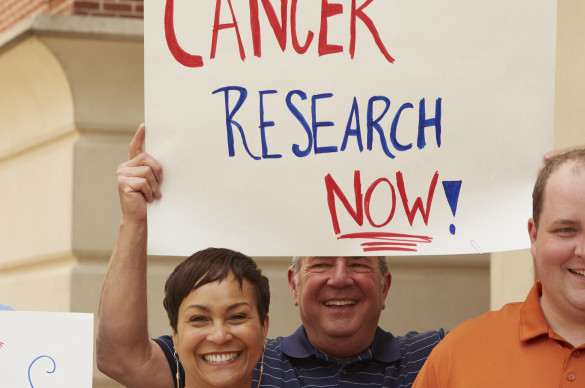 Man holding sign that reads: Cancer Research Now!