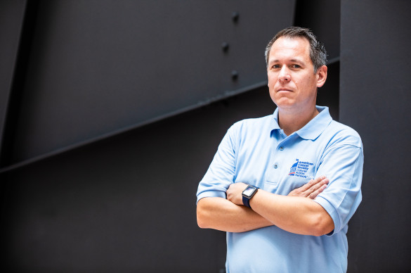 Man with arms crossed, serious expression and wearing an ACS CAN polo