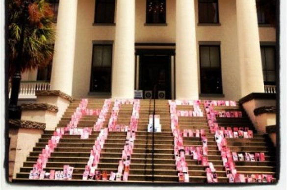 Photo of a building with columns with the words "Hope" and "Cure" written on the front steps with pink bags