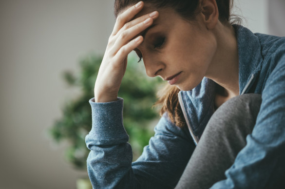 woman with head in hands looking down serious expression