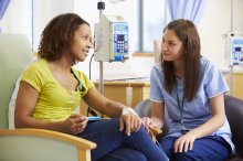A nurse comforts a cancer patient in treatment.