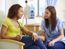 A nurse comforts a cancer patient in treatment.