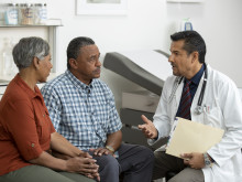 Doctor discussing with elderly patient and his partner