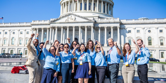 volunteers with raised hands in advocacy in front of capitol building