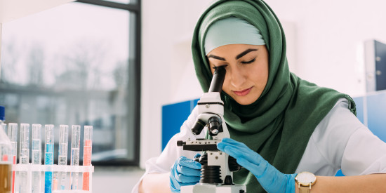 woman looking through a microscope