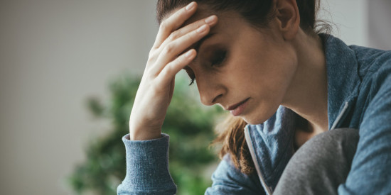 woman with head in hands looking down serious expression