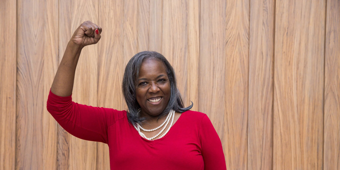 female participant raising fist and smiling at the camera