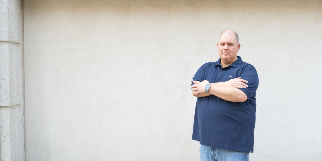 large man looking directly at camera with arms crossed
