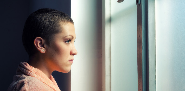 Woman looking out of a window looking concerned