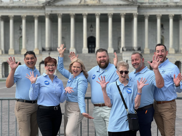 Volunteers posing in front of the US capitol with hands out in excitement