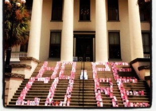 Photo of a building with columns with the words "Hope" and "Cure" written on the front steps with pink bags