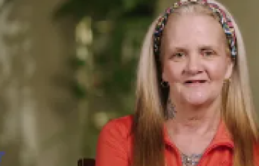 video still of woman indoors being interviewed